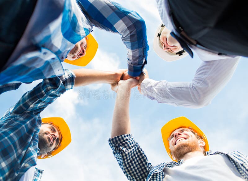 Close up of builders in hardhats making high five royalty free stock images