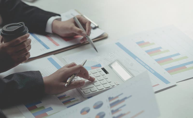 Close up business analyst pointing to earnings charts and graphs. Analysts are calculating the numbers with a calculator for good stock photography