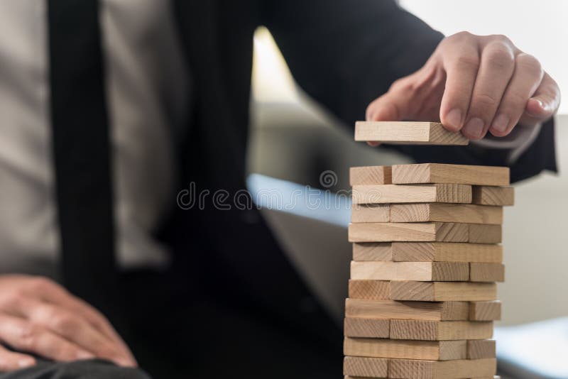 A close up of a business man carefully building a tower