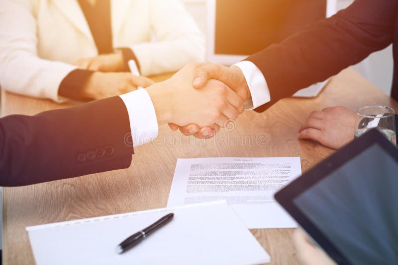 Close up of business people shaking hands at meeting or negotiation in the office. Partners are satisfied because