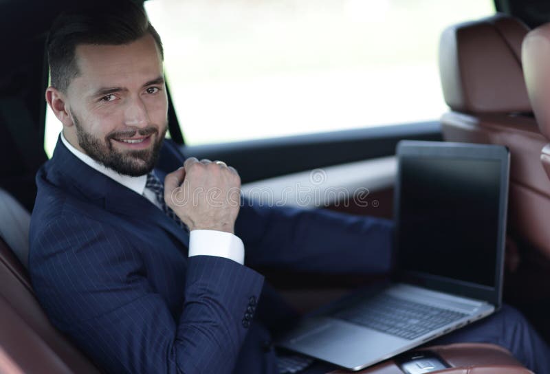 Close-up of a businessman with a laptop sitting in the car royalty free stock image