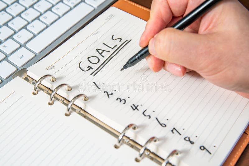 Close-up of a businessman`s hand writing goals and list in the diary