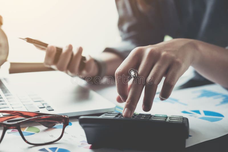 Close up of businesswoman or accountant hand holding pen working on calculator to calculate business data, accountancy document