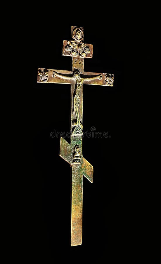 Close-up of Byzantine bronze cross with sun shining on it isolated on black