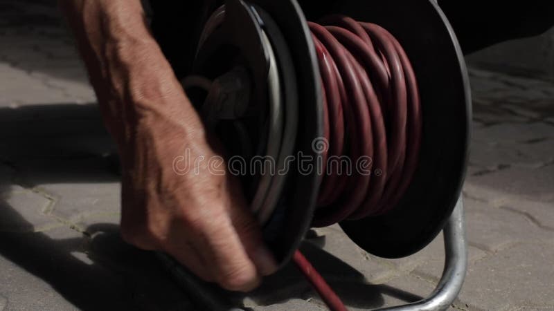 Close-up of the Cable Pulled from the Extension Drum of the Cable Reel,  Male Hands Wind the Extension Cable Onto the Stock Video - Video of  current, amper: 246682533