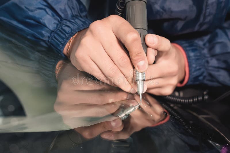 Close up Car glaze worker fixing and repairing a windshield or windshield of a car at a garage service station. Drill. Glass for repair royalty free stock image Close up Car glaze worker fixing and repairing a windshield or windshield of a car at a garage service station. Drill. Glass for repair royalty free stock image