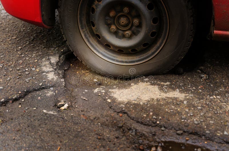 A Closeup of a Car Wheel Stuck in a Pothole in the Asphalt. Stock
