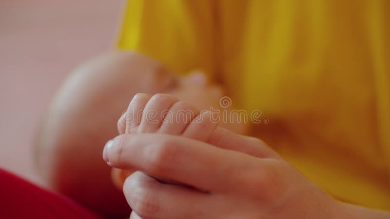 Close-up of caring mother gently caressing small hand infant baby