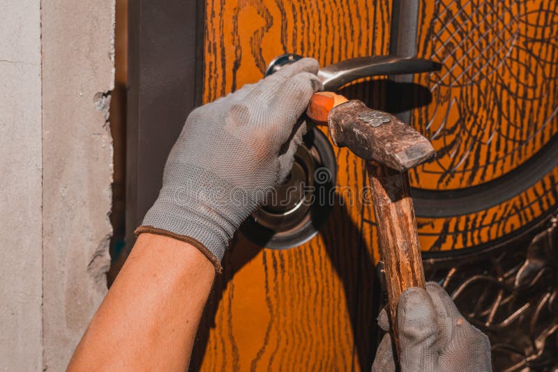 Closeup, the Carpenter Installs a Custom Lock in the Front Metal Door