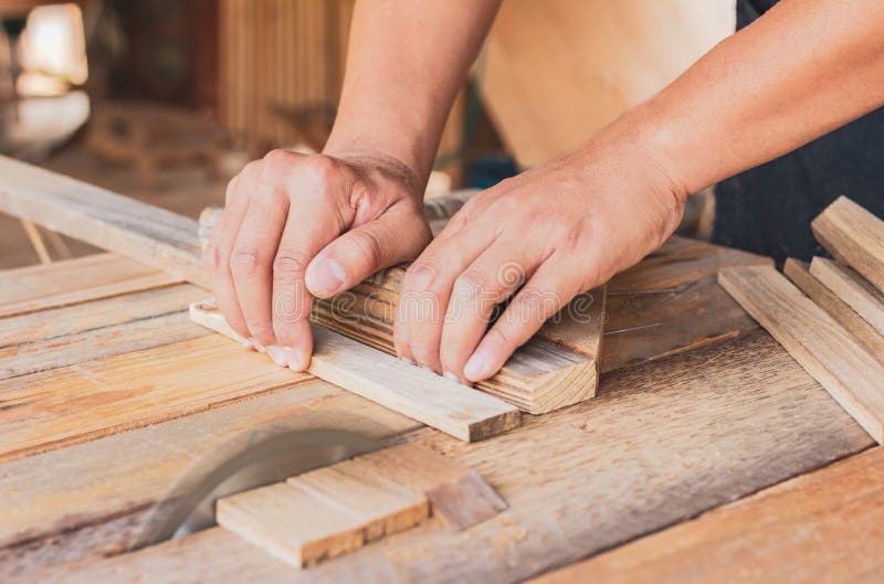 Close up, carpenter man cutting a plank of wood in the working using a circular saw in workshop