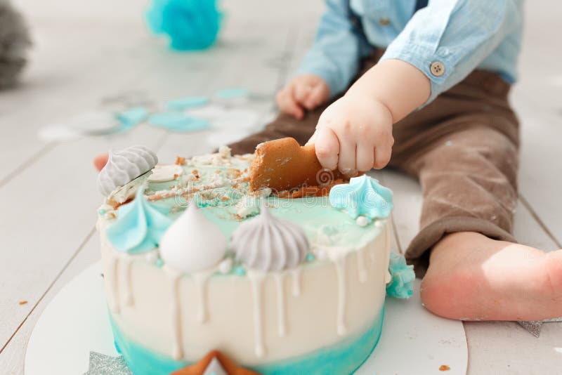 Close up of a caucasian birthday boy legs and arms while he destroys and smashes his cream cake with mint and white