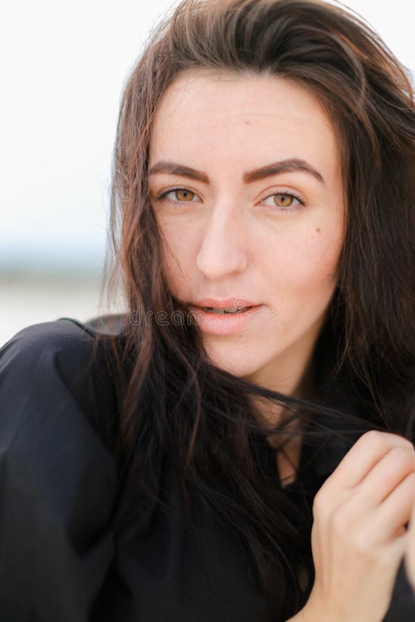 Close up of caucasian female person without makep and cute smile, having black hair and brown eyes. stock photography