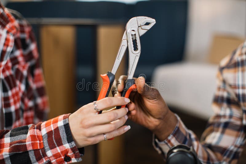 Close up of woman giving pliers to man at new home royalty free stock photography