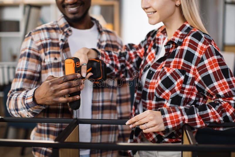 Close up of couple using screwdriver for assembling bookcase stock photography