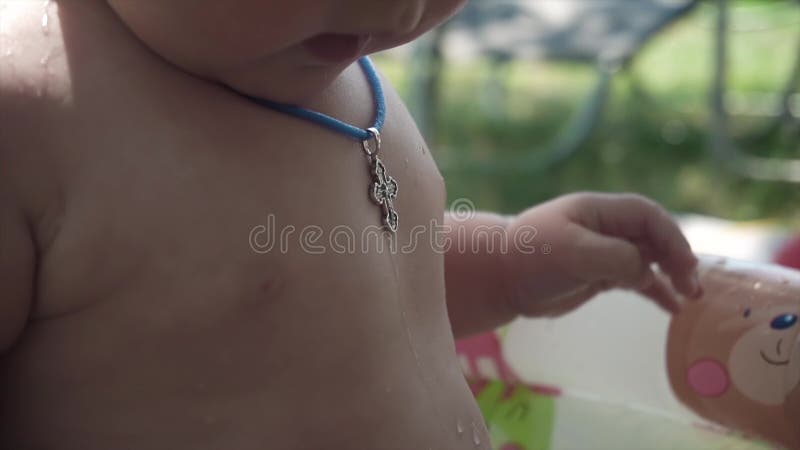 Close-up of a Christian cross on the body of a baby bathing in a tub