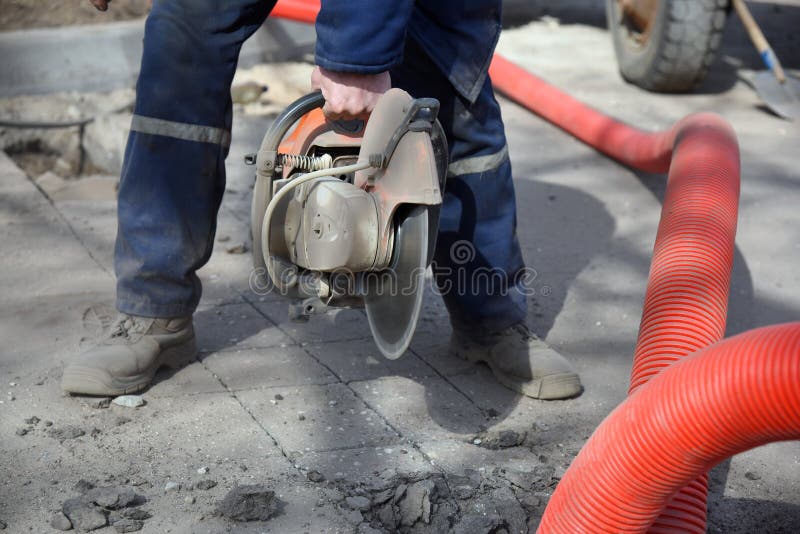 Closeup of a Circular Saw in the Hands of a Worker Cutting Asphalt
