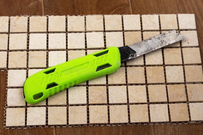Construction Knife with Replaceable Blades Lying on a Ceramic Tile