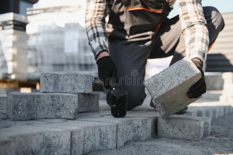 Close-up of construction worker installing and laying pavement stones on terrace, road or sidewalk. Worker using stones stock photos