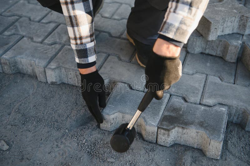 Close-up of construction worker installing and laying pavement stones on terrace, road or sidewalk. Worker using stones royalty free stock photo