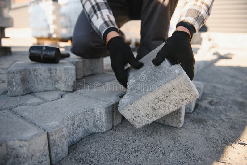 Close-up of construction worker installing and laying pavement stones on terrace, road or sidewalk. Worker using stones stock photo