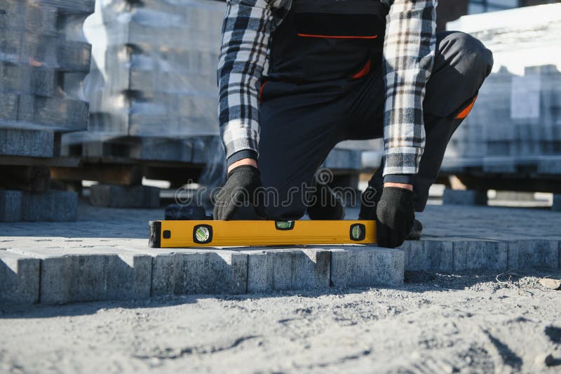 Close-up of construction worker installing and laying pavement stones on terrace, road or sidewalk. Worker using stones stock photos