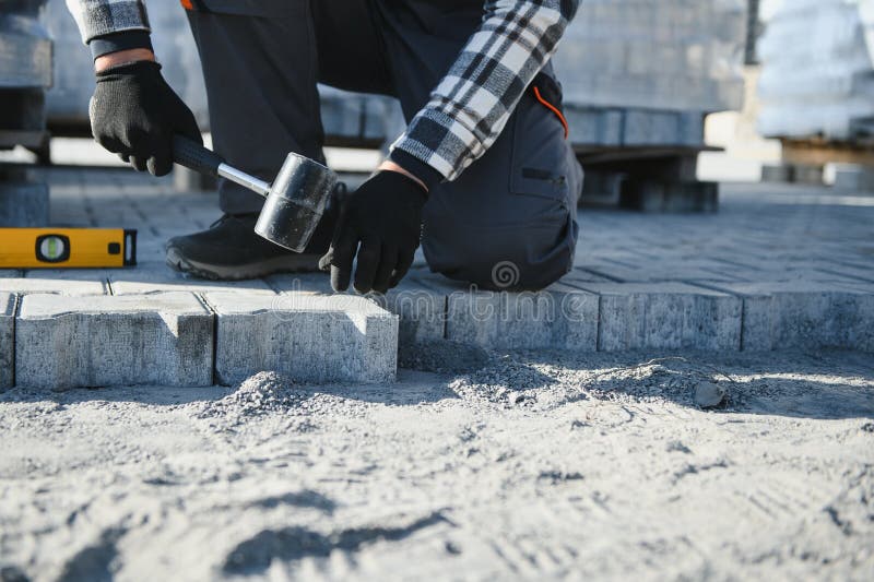 Close-up of construction worker installing and laying pavement stones on terrace, road or sidewalk. Worker using stones royalty free stock image