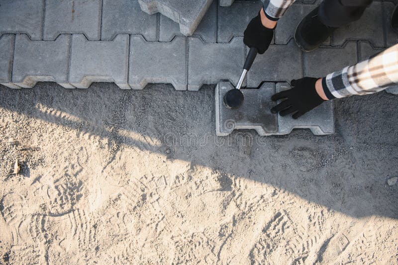 Close-up of construction worker installing and laying pavement stones on terrace, road or sidewalk. Worker using stones stock image