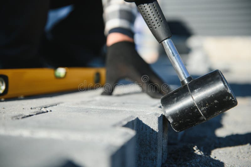Close-up of construction worker installing and laying pavement stones on terrace, road or sidewalk. Worker using stones stock photo