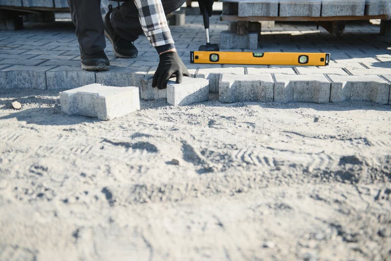 Close-up of construction worker installing and laying pavement stones on terrace, road or sidewalk. Worker using stones stock photos
