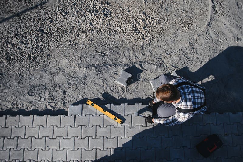 Close-up of construction worker installing and laying pavement stones on terrace, road or sidewalk. Worker using stones stock images