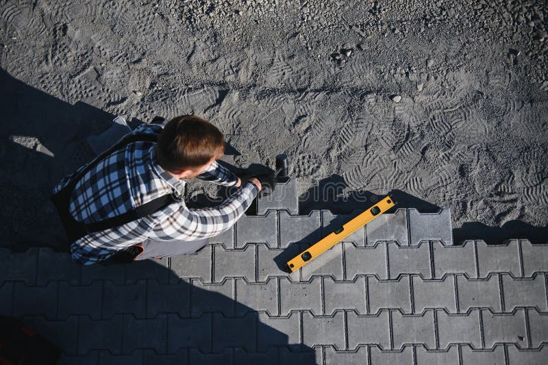 Close-up of construction worker installing and laying pavement stones on terrace, road or sidewalk. Worker using stones stock images