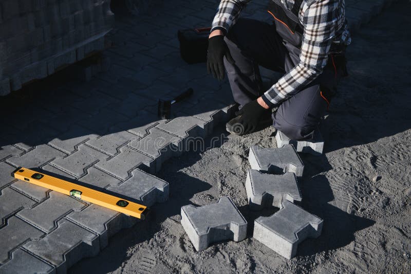 Close-up of construction worker installing and laying pavement stones on terrace, road or sidewalk. Worker using stones royalty free stock photos