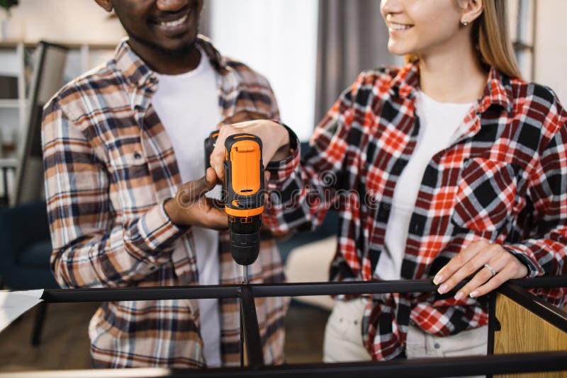 Close up of couple using screwdriver for assembling bookcase royalty free stock photography