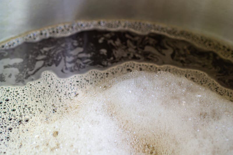 Close-up of craft beer and foam in a fermentation container. Process of making home beer from malt. Craft beer from barley and stock photo
