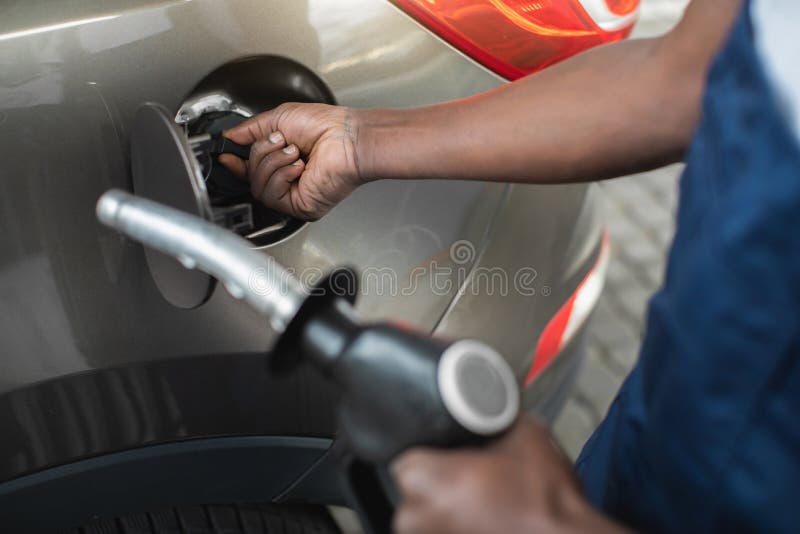 Close up cropped shot of a gas station worker& x27;s hands with filling gun, ready to refueling the car with gas or petrol at. A gas station