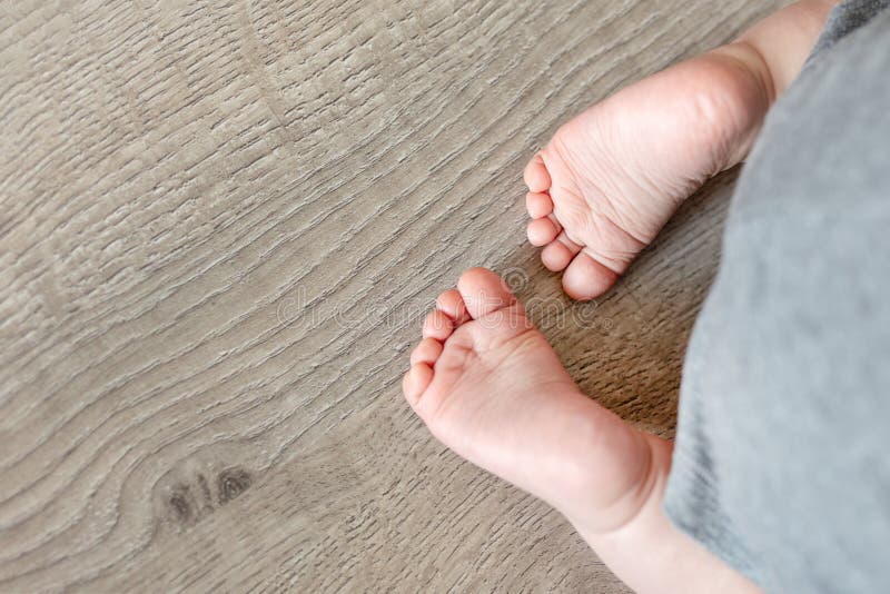 Close-up cute infant baby feet on wooden floor background. Funny adorable heels. Tender childs toe royalty free stock images Close-up cute infant baby feet on wooden floor background. Funny adorable heels. Tender childs toe royalty free stock images