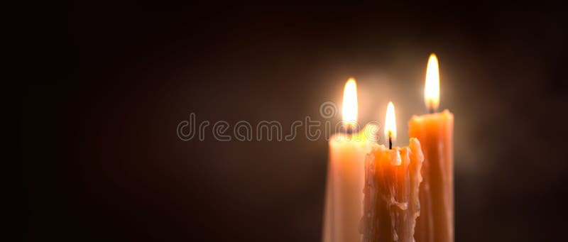 Close up da chama de vela em um fundo escuro Projeto da beira da luz da vela Velas derretidas da cera que queimam-se na noite imagem de stock Close up da chama de vela em um fundo escuro Projeto da beira da luz da vela Velas derretidas da cera que queimam-se na noite imagem de stock