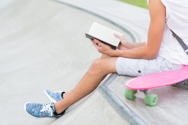 Close up da leitura do homem novo no parque do skate imagem de stock Close up da leitura do homem novo no parque do skate imagem de stock