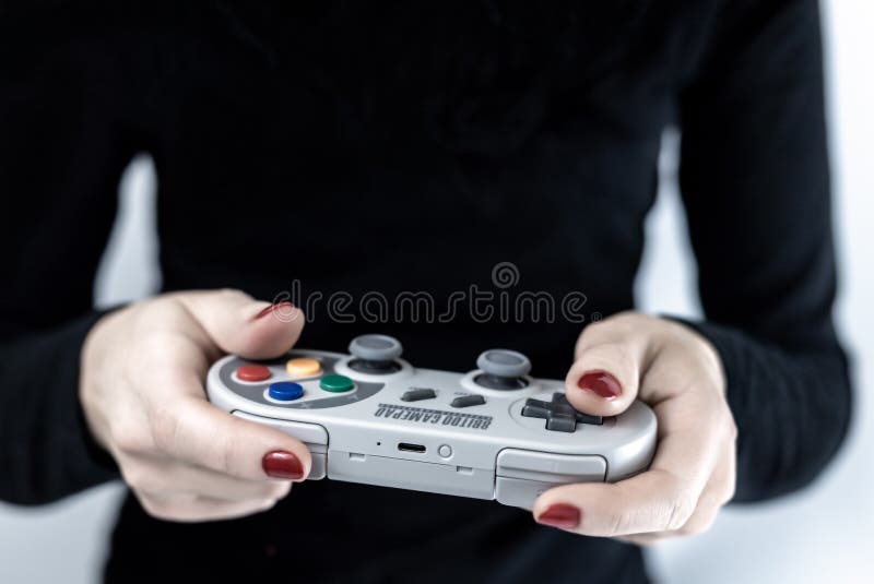 Close up da mulher com o verniz para as unhas vermelho que guarda um controlador do jogo com o projeto retro do Super Nintendo qu foto de stock royalty free Close up da mulher com o verniz para as unhas vermelho que guarda um controlador do jogo com o projeto retro do Super Nintendo qu foto de stock royalty free
