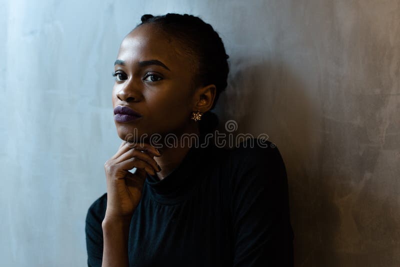 Close-up da mulher negra nova pensativa que olha afastado com mão sob o queixo, fundo cinzento imagens de stock royalty free Close-up da mulher negra nova pensativa que olha afastado com mão sob o queixo, fundo cinzento imagens de stock royalty free