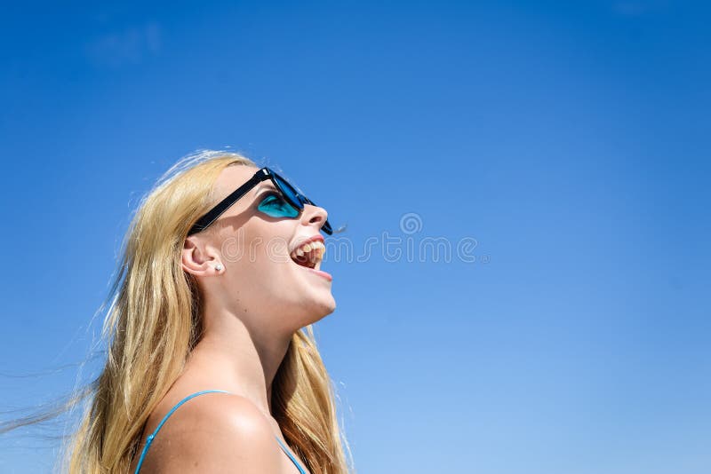 Close up da senhora bonita loura nova feliz deleitada nos óculos de sol sobre o céu azul no dia de verão fora fotografia de stock royalty free Close up da senhora bonita loura nova feliz deleitada nos óculos de sol sobre o céu azul no dia de verão fora fotografia de stock royalty free