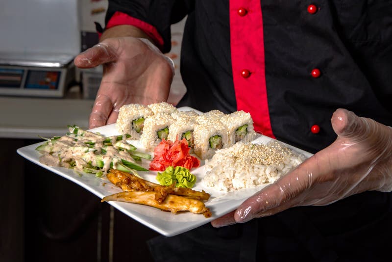 Close up das mãos do cozinheiro chefe que rolam acima do ajuste do sushi na placa na cozinha fotografia de stock royalty free Close up das mãos do cozinheiro chefe que rolam acima do ajuste do sushi na placa na cozinha fotografia de stock royalty free