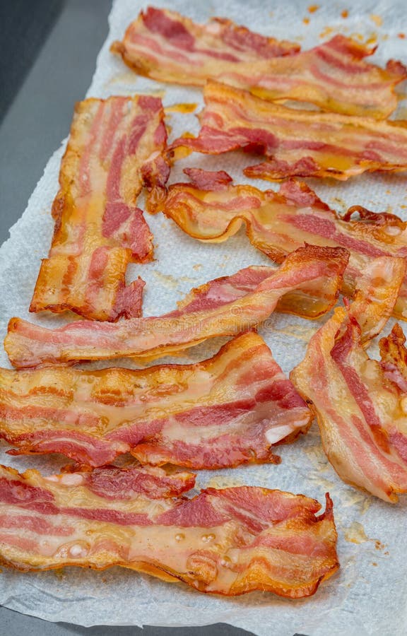 Close-up of appetizing slices of smoked bacon. Isolated on white background. With baking paper. Cooked in the oven, very crispy. Close-up of appetizing slices of smoked bacon. Isolated on white background. With baking paper. Cooked in the oven, very crispy