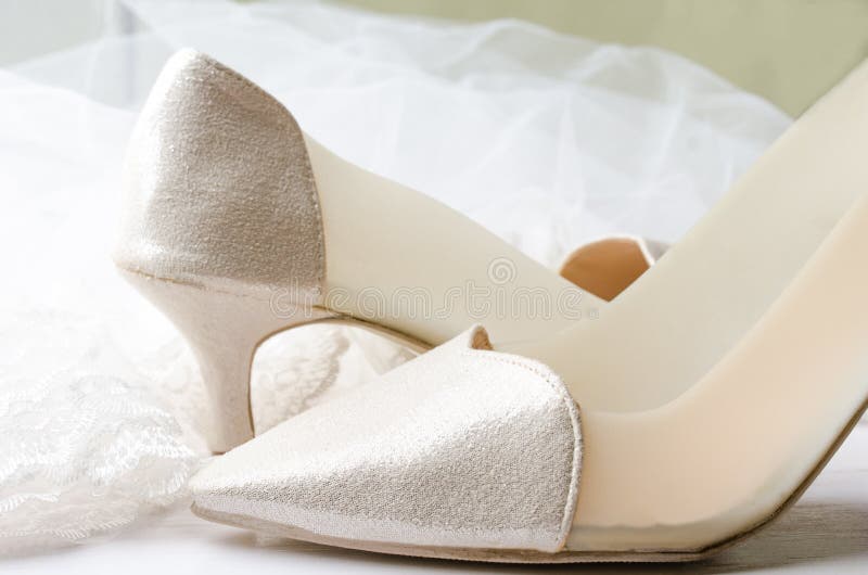 Close-up de sapatas do casamento com o véu do casamento do laço em de madeira branco fotos de stock Close-up de sapatas do casamento com o véu do casamento do laço em de madeira branco fotos de stock