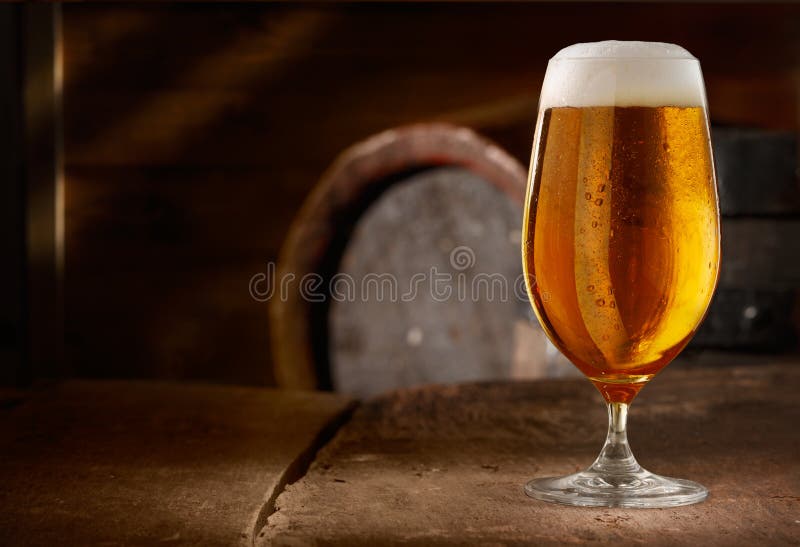 Closeup of a glass of fresh foamy beer on a table in a vintage beer cellar. Closeup of a glass of fresh foamy beer on a table in a vintage beer cellar