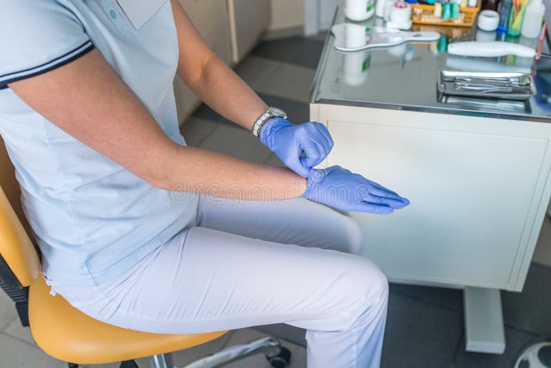 Closeup Of Dentist Female Putting On Blue Disposable Gloves Stock