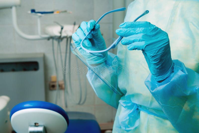 Close up of a dentist`s hands holding a protective plastic screen in his office stock images