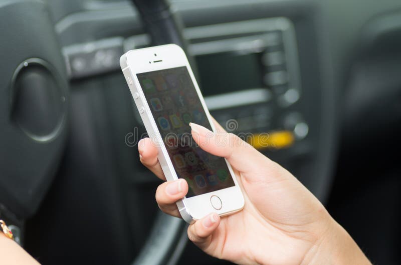 Close up dentro do veículo da mão que guarda o smartphone, o volante e o fundo interior preto, conceito fêmea do motorista fotografia de stock Close up dentro do veículo da mão que guarda o smartphone, o volante e o fundo interior preto, conceito fêmea do motorista fotografia de stock