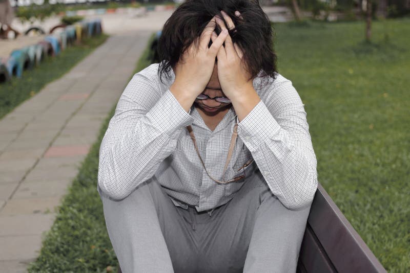 Close up depressed stressed young Asian business man suffering from severe depression in the park. Close up depressed stressed young Asian business man stock photos Close up depressed stressed young Asian business man suffering from severe depression in the park. Close up depressed stressed young Asian business man stock photos