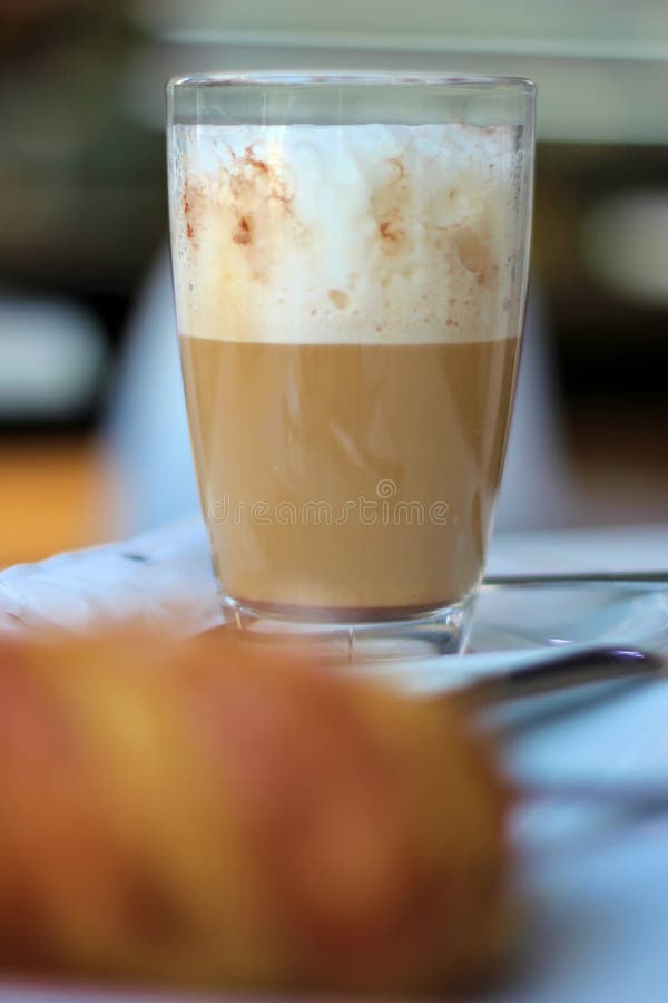Close-up detail of a Cafe latte and a croissant on a coffee shop table royalty free stock images Close-up detail of a Cafe latte and a croissant on a coffee shop table royalty free stock images